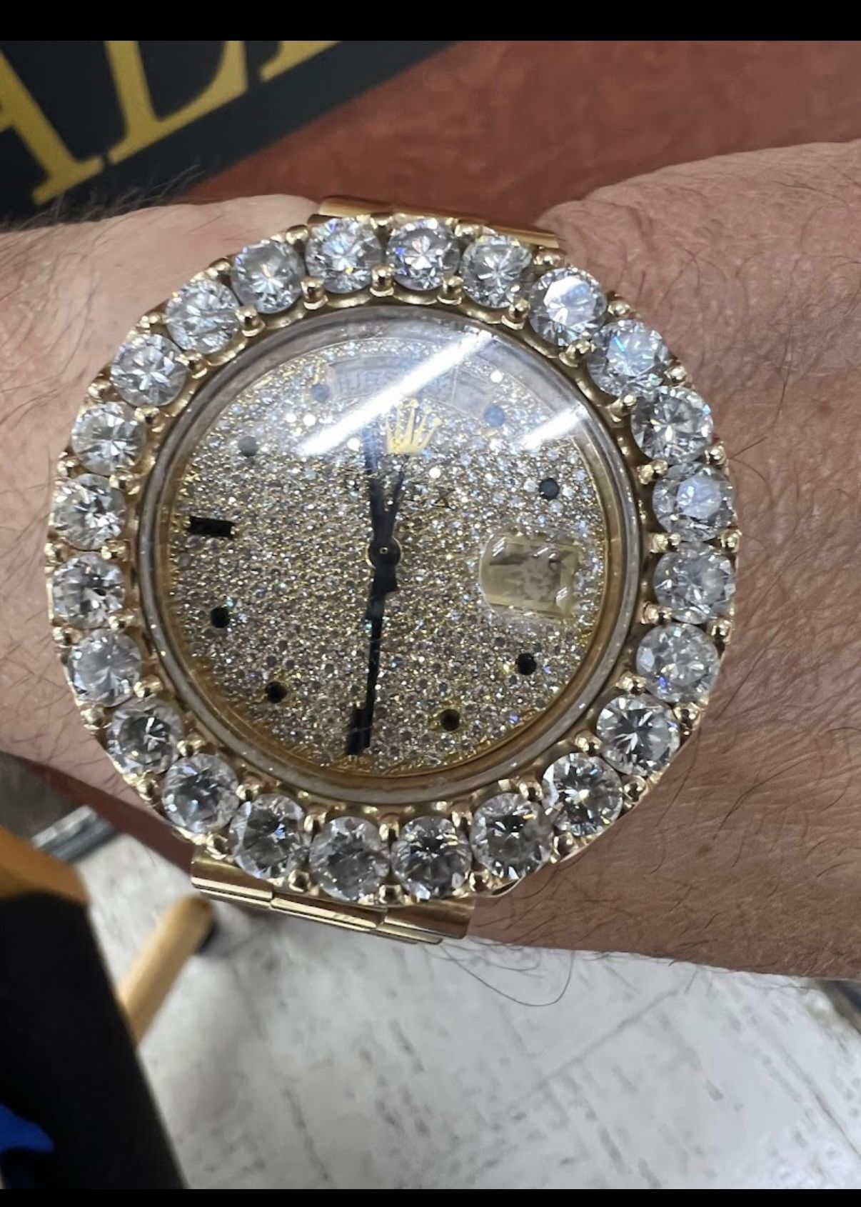 Close-up of a diamond-encrusted gold wristwatch on a person’s wrist