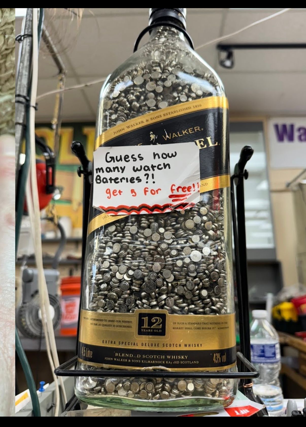 Large bottle of pebbles with a sign asking, “Guess how many coins? $25 for free!”