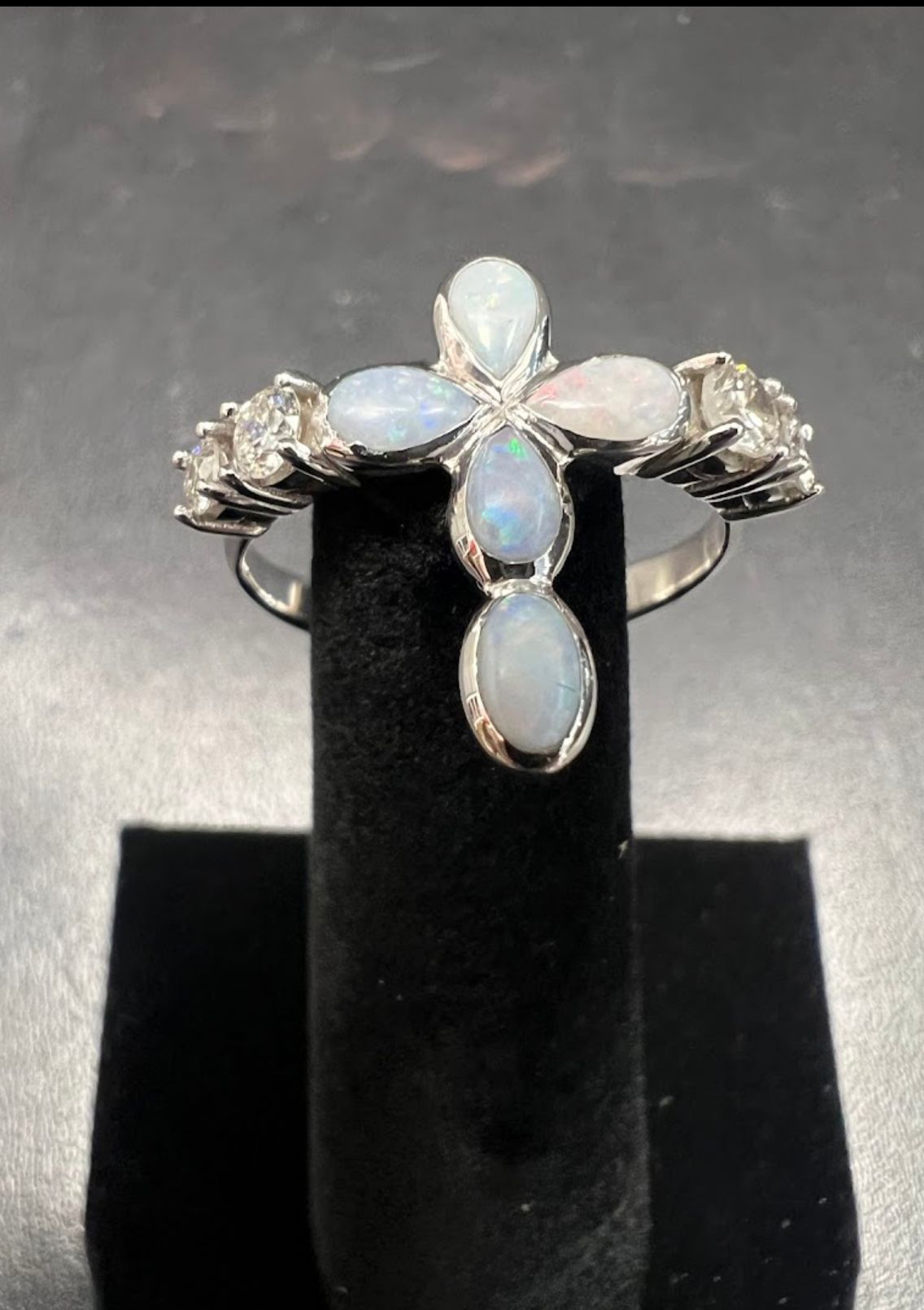Silver ring with oval opal stones displayed on a black stand