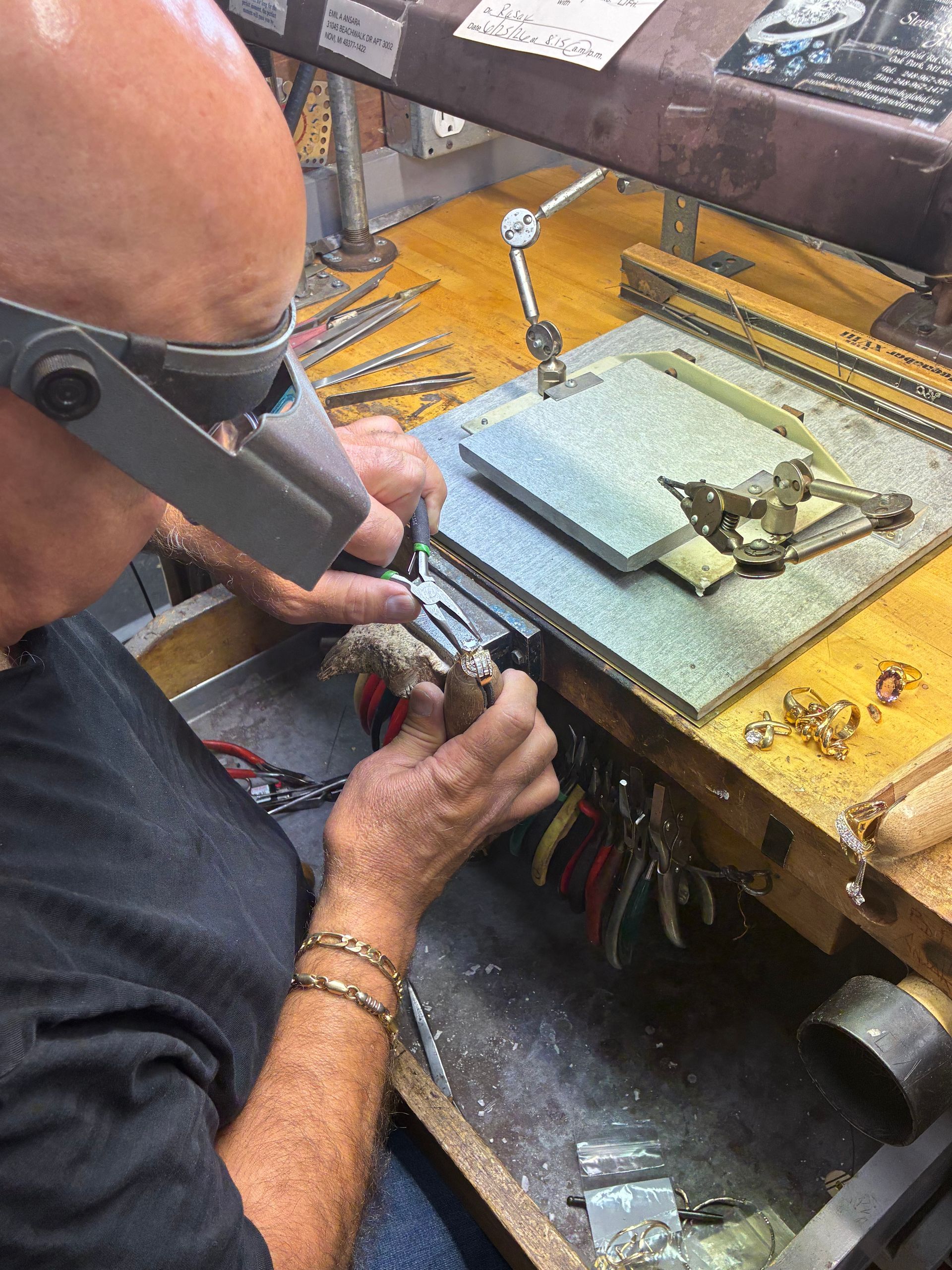 Person using a soldering iron to repair electronics at a cluttered workbench.