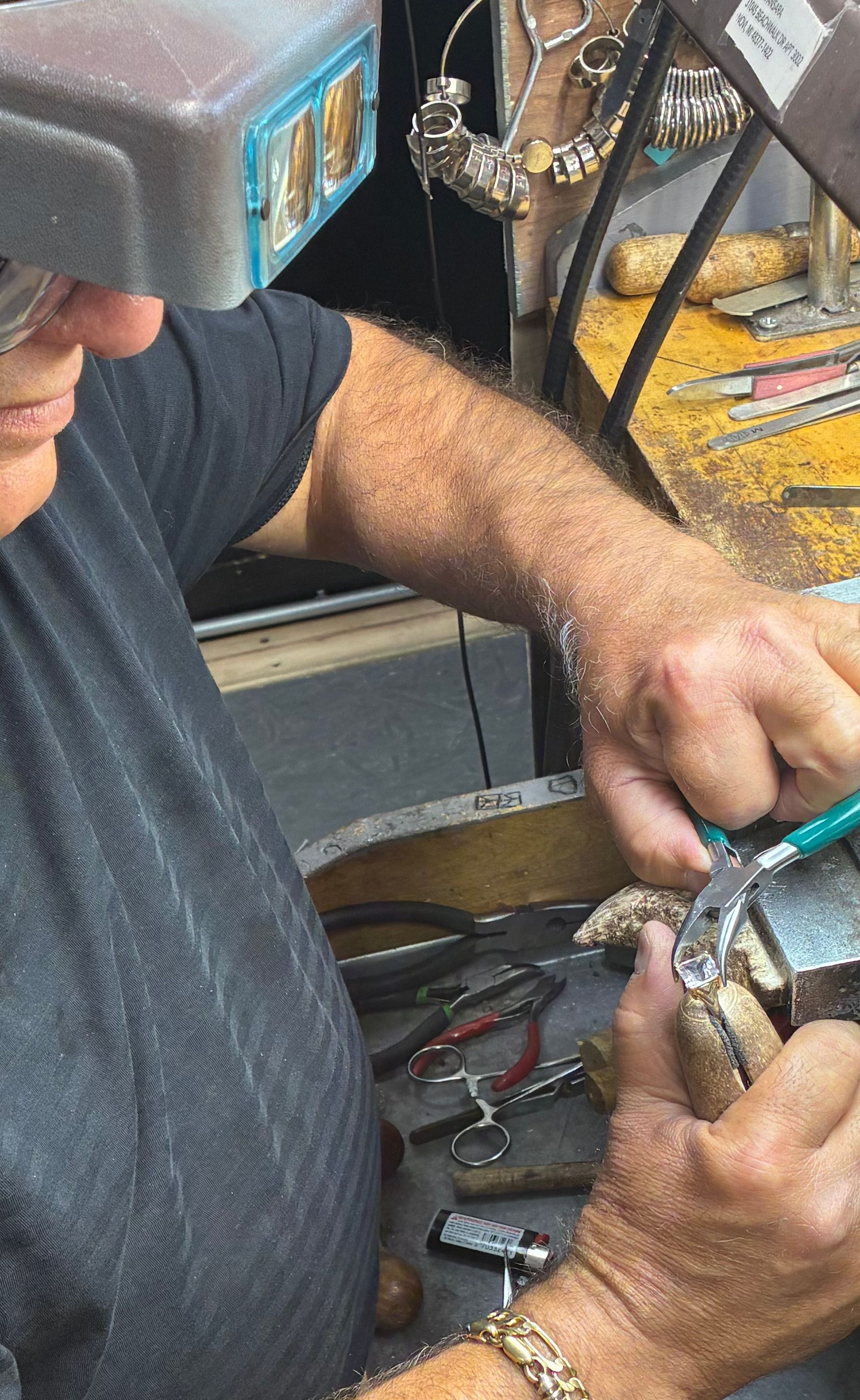 Mechanic wearing a headlamp repairs a metal part at a workbench with tools nearby
