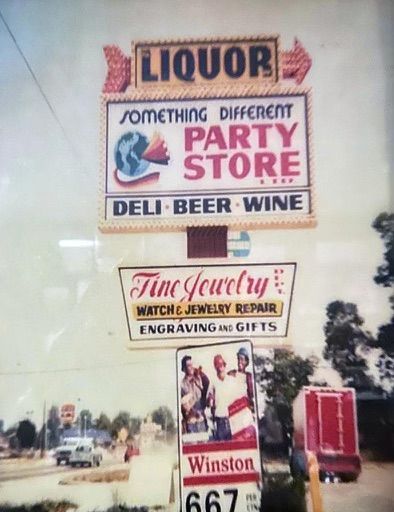 Liquor and party store signs with deli, beer, wine, jewelry repair, and engravings ads on a roadside billboard