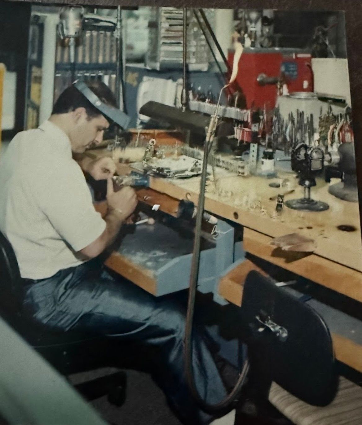 Person working at a cluttered electronics repair bench with tools and equipment