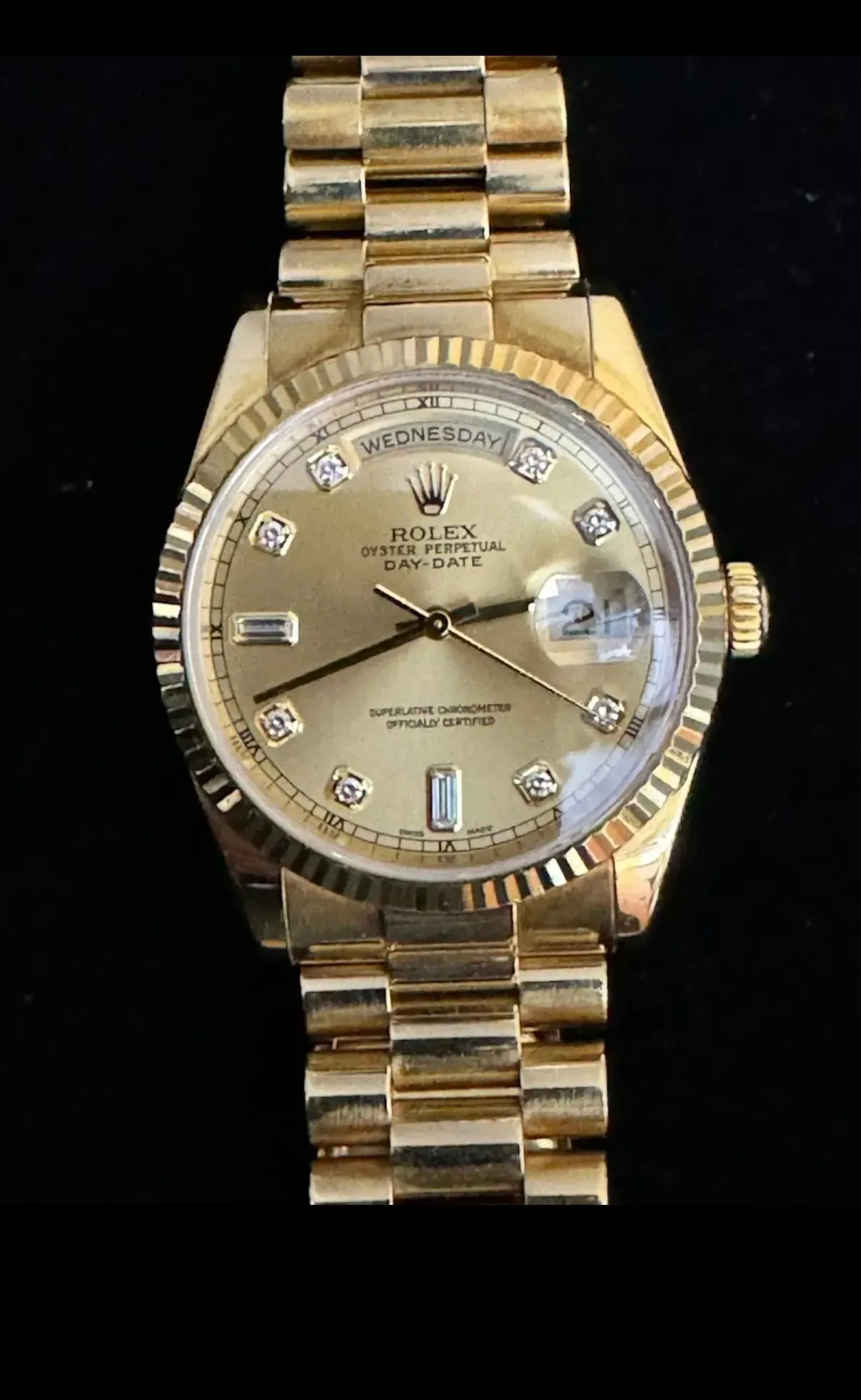 Gold wristwatch with diamond hour markers and a fluted bezel on a matching gold band