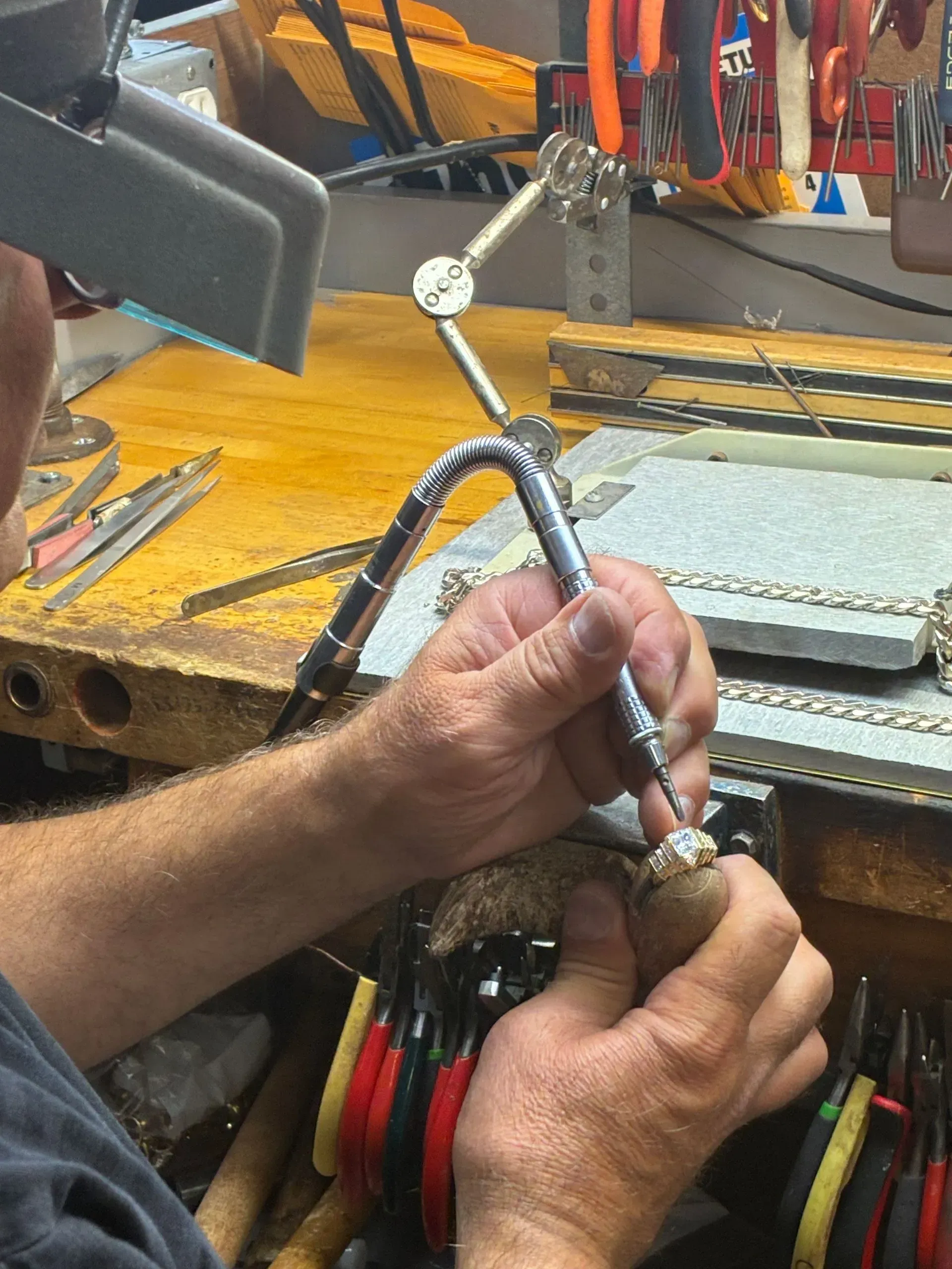 Hands working on a cable assembly at a cluttered electronics workbench.