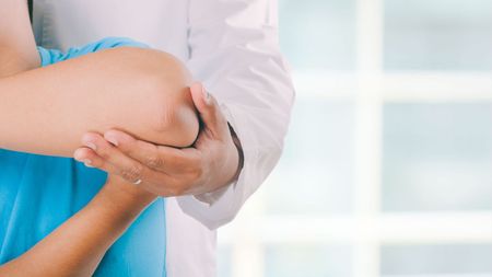 Un medico sta esaminando il gomito di un paziente in un ospedale.