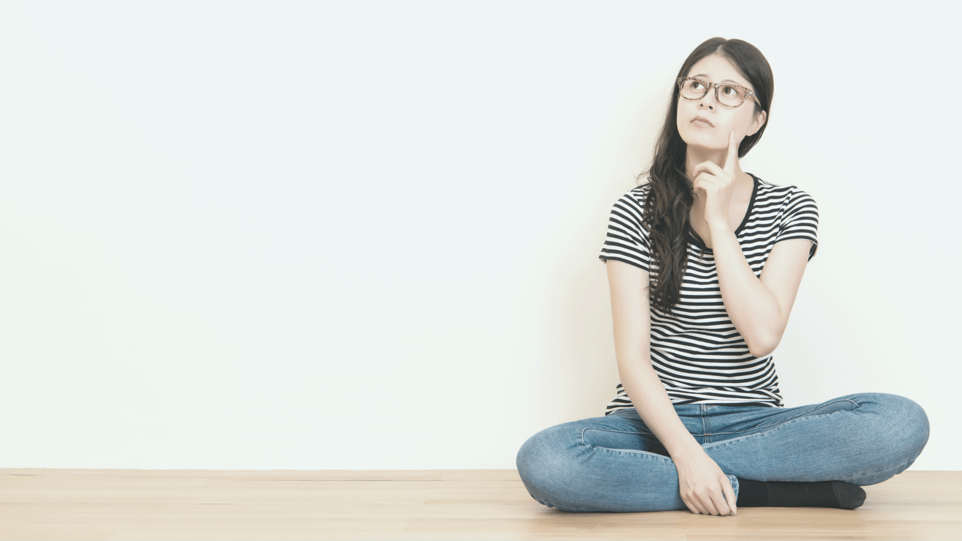 a woman sat on the floor looking worried, holding a hand up to her neck in self comfort