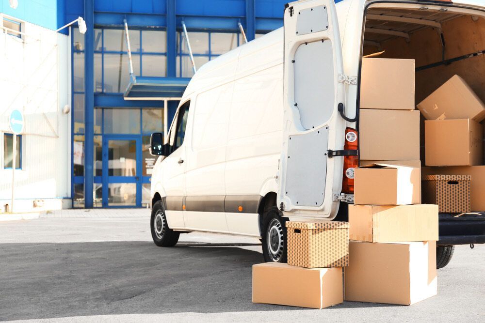 A White Van is Loaded With Boxes in Front of a Building — A-Team Delivery Services Pty Ltd in Newcastle, NSW