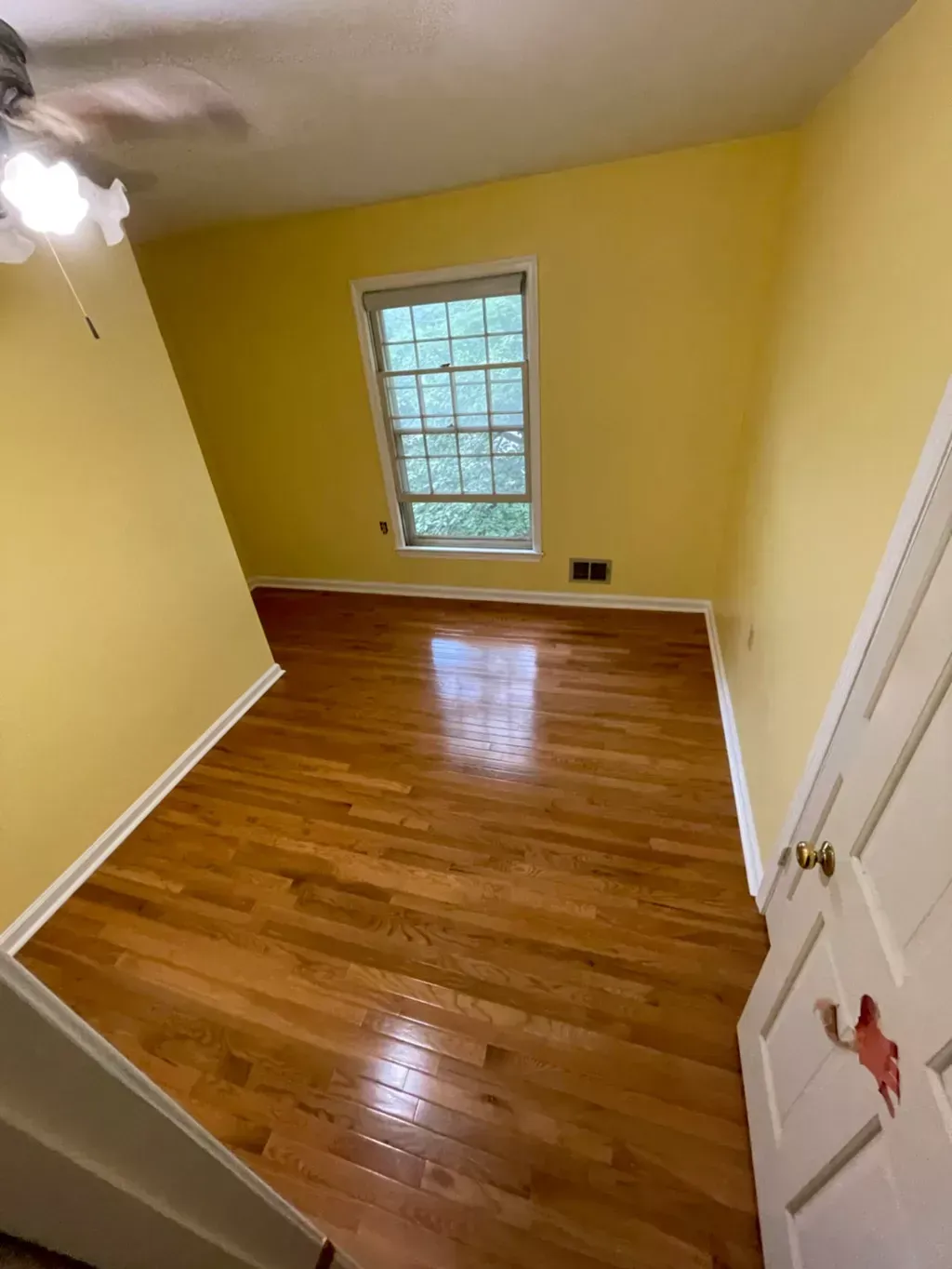 An empty room with hardwood floors and yellow walls.