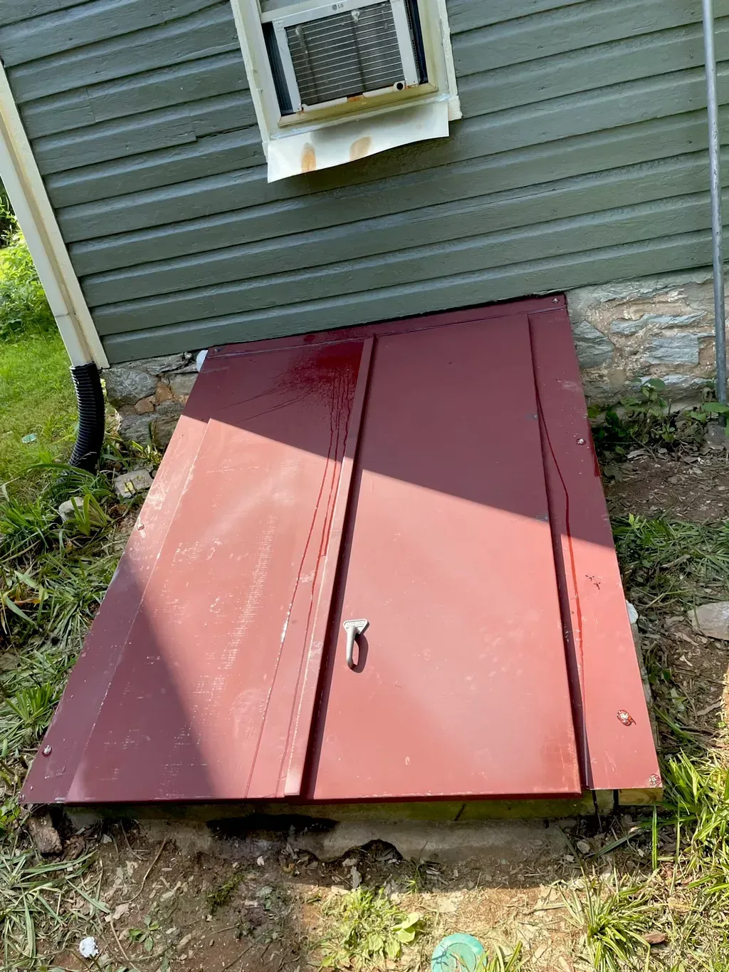 A red door is sitting in the dirt next to a house.