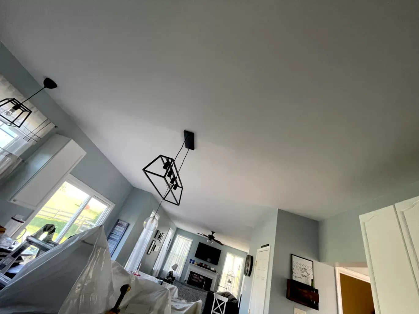 A living room with a ceiling fan and a chandelier hanging from it.
