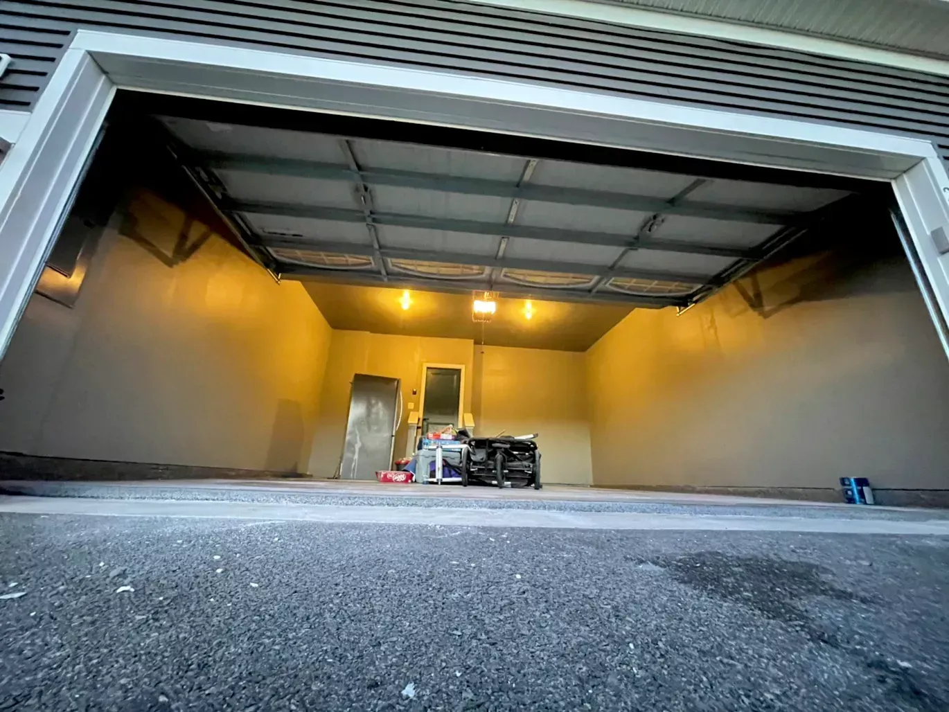 The inside of a garage with the door open and lights on.