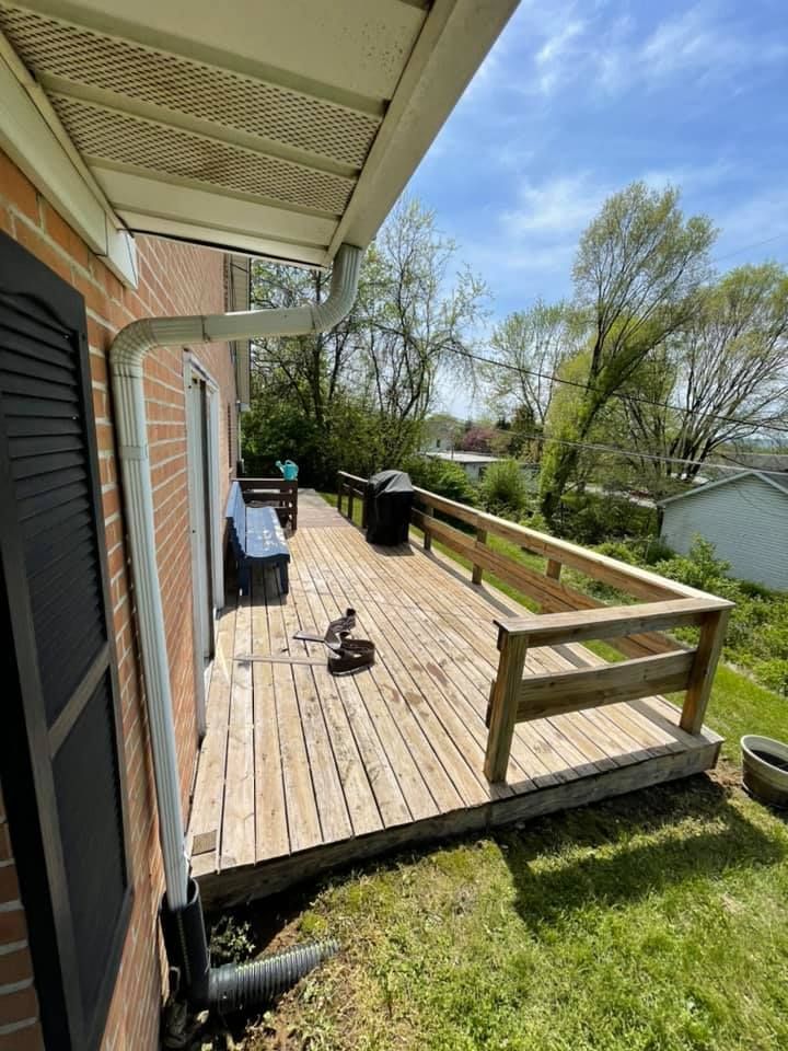 A wooden deck is sitting on the side of a brick house.