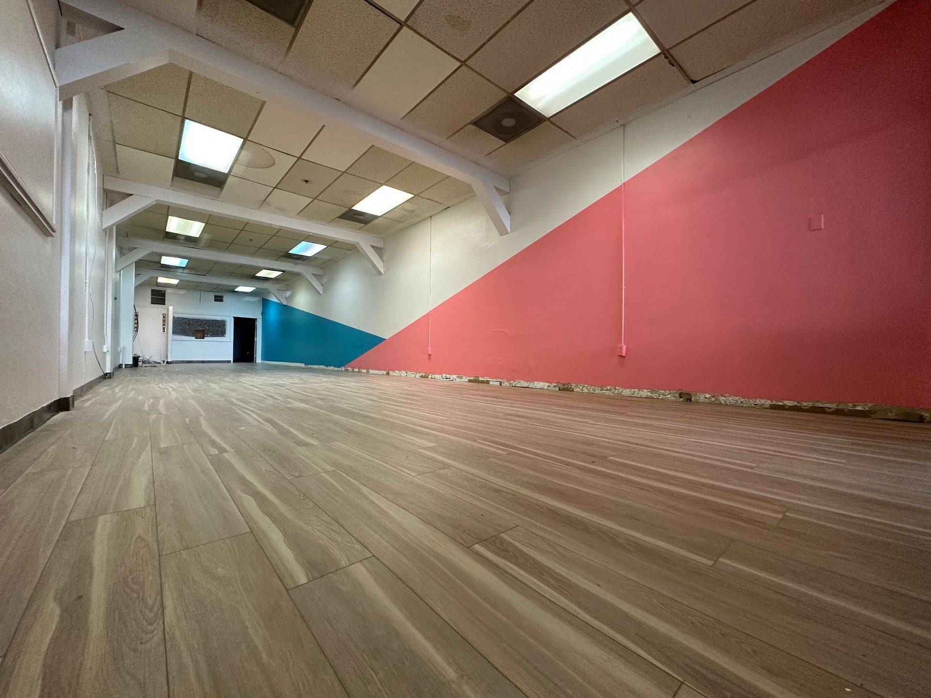 An empty room with a wooden floor and red and blue walls