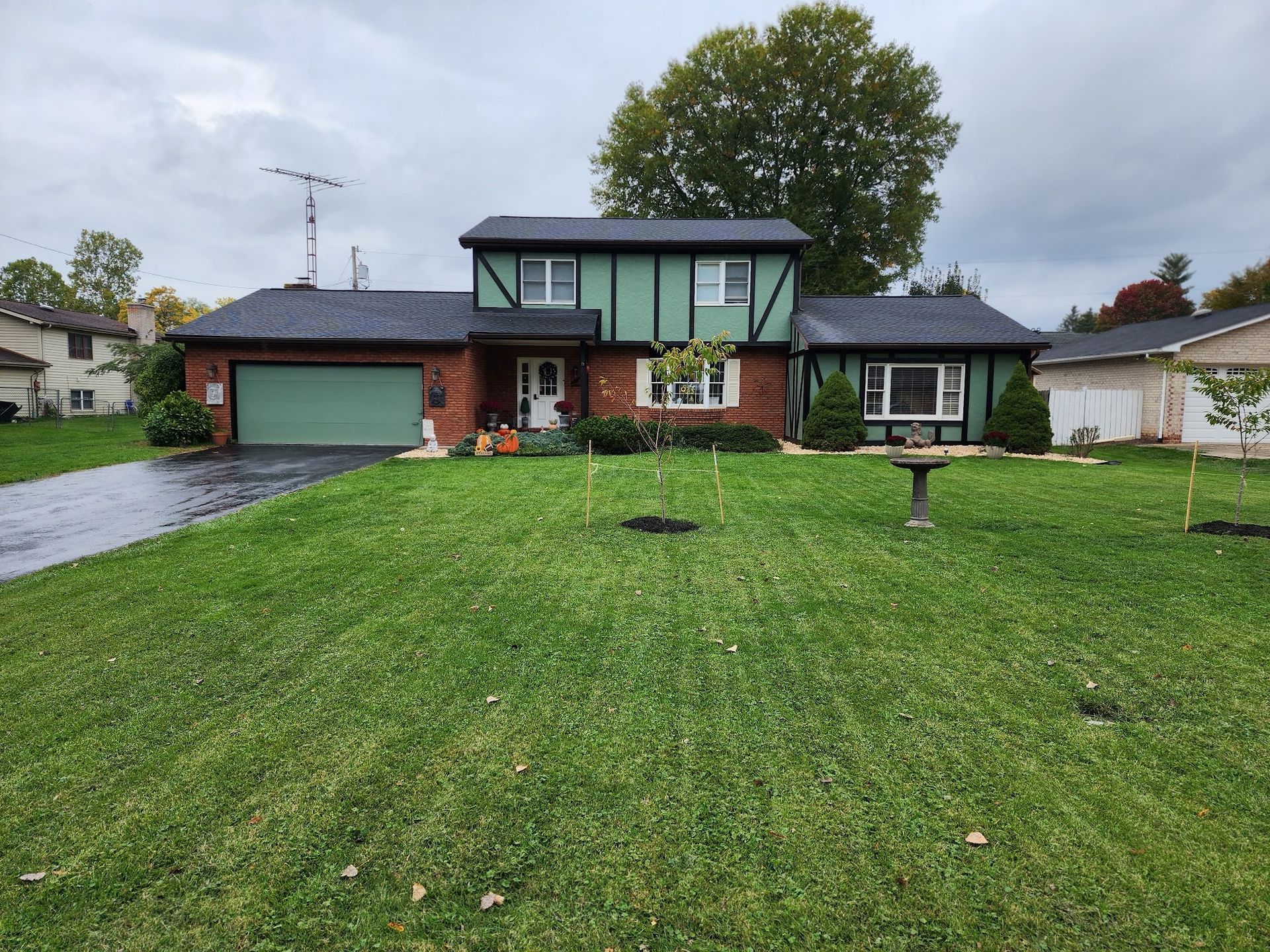 A brick house with a green roof and a large lawn in front of it.