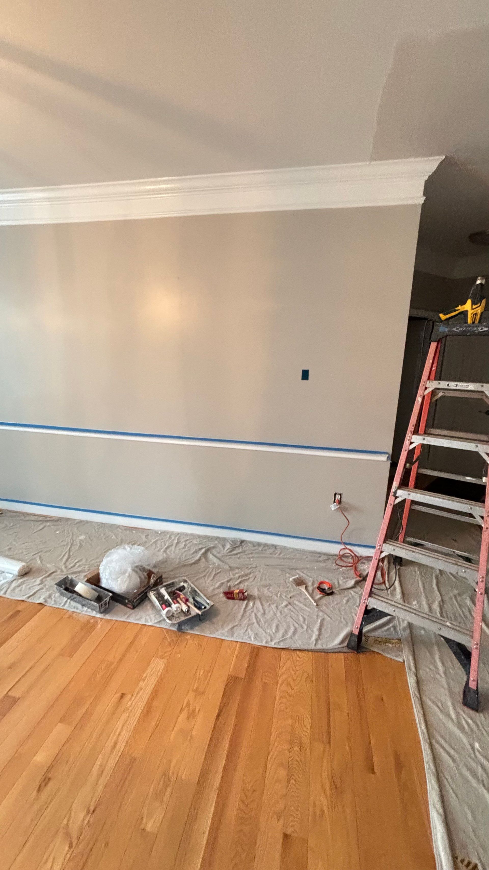 A living room is being painted with a ladder.