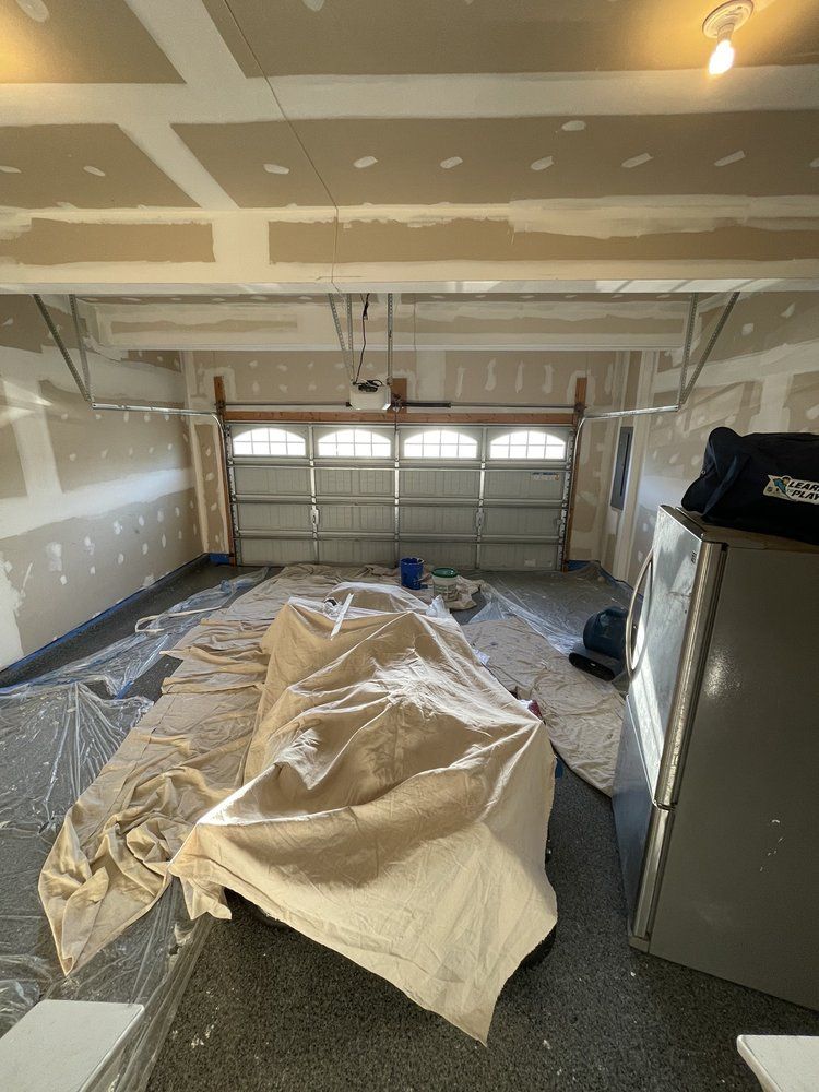 A garage is being painted with a tarp on the floor.