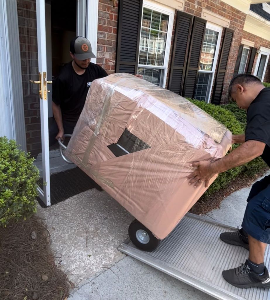 Two men are pushing a large box on a dolly.