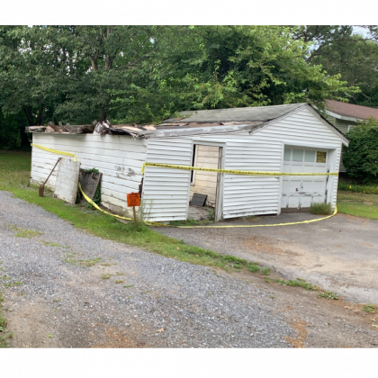 A white garage with a yellow tape around it