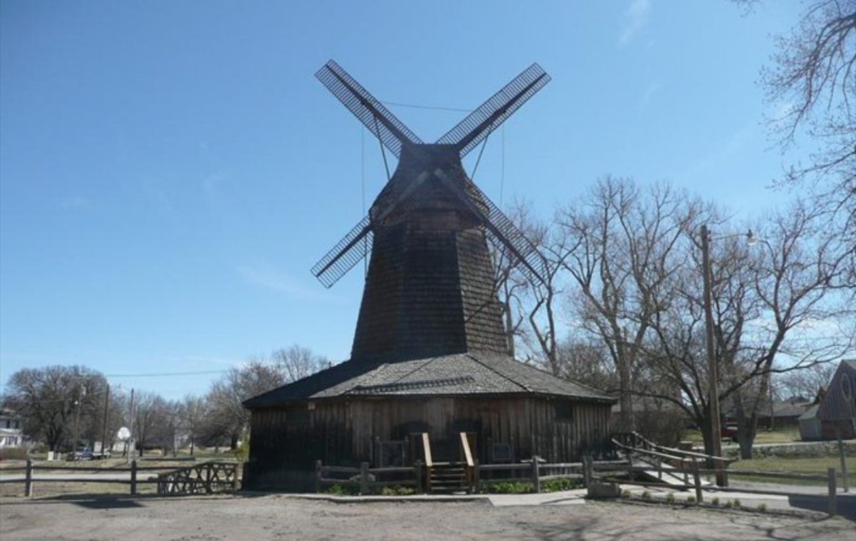 Historic wooden windmill under a clear blue sky in a rural setting