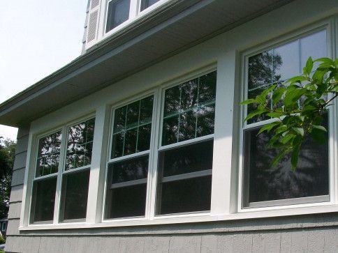 Row of white-trimmed windows on a house exterior under a sloped roof