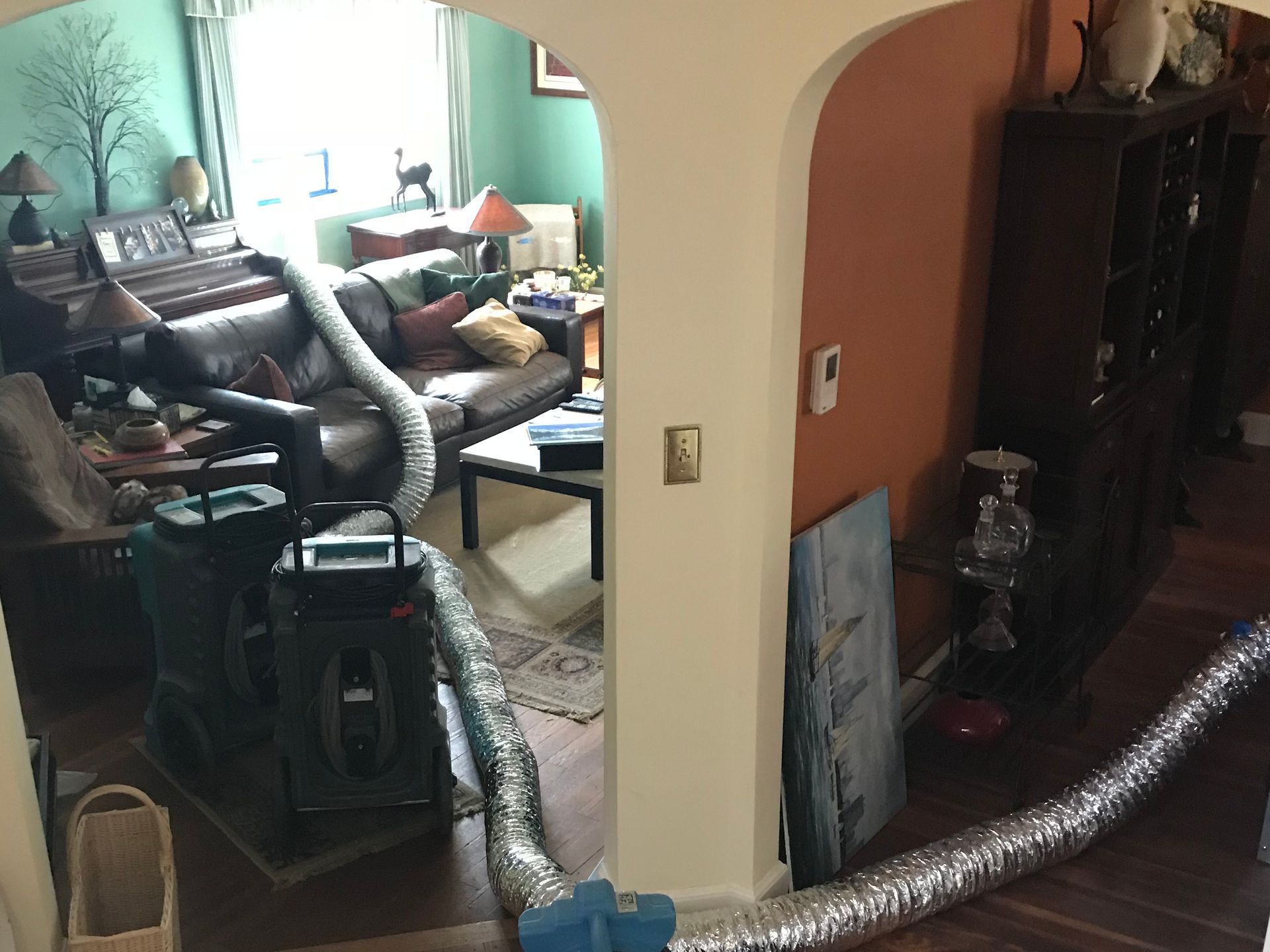 Living room with furniture, rugs, and silver flexible ducting across the floor