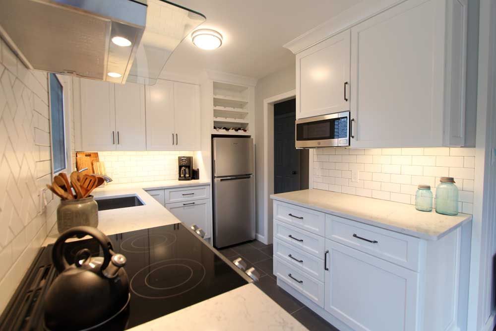 Bright modern white kitchen with stainless steel appliances and black countertops