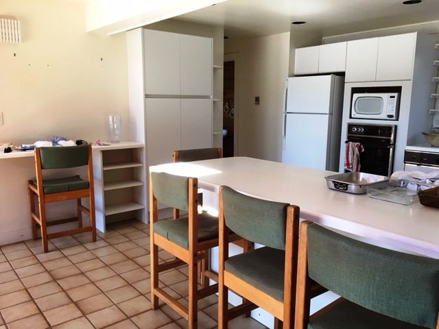 Bright kitchen with tiled floor, white cabinets, and a dining table with chairs in the foreground