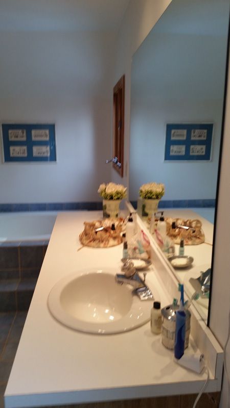 Bathroom vanity with white countertop, sink, mirror, and toiletries