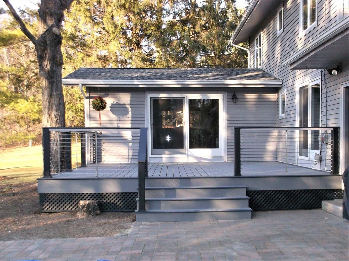 Back deck with gray steps, black railings, and sliding glass doors on a house