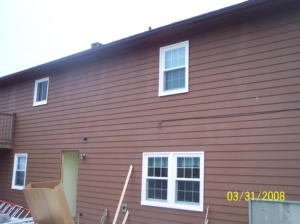 Brown house exterior with white-trimmed windows and a green door under a sloped roof