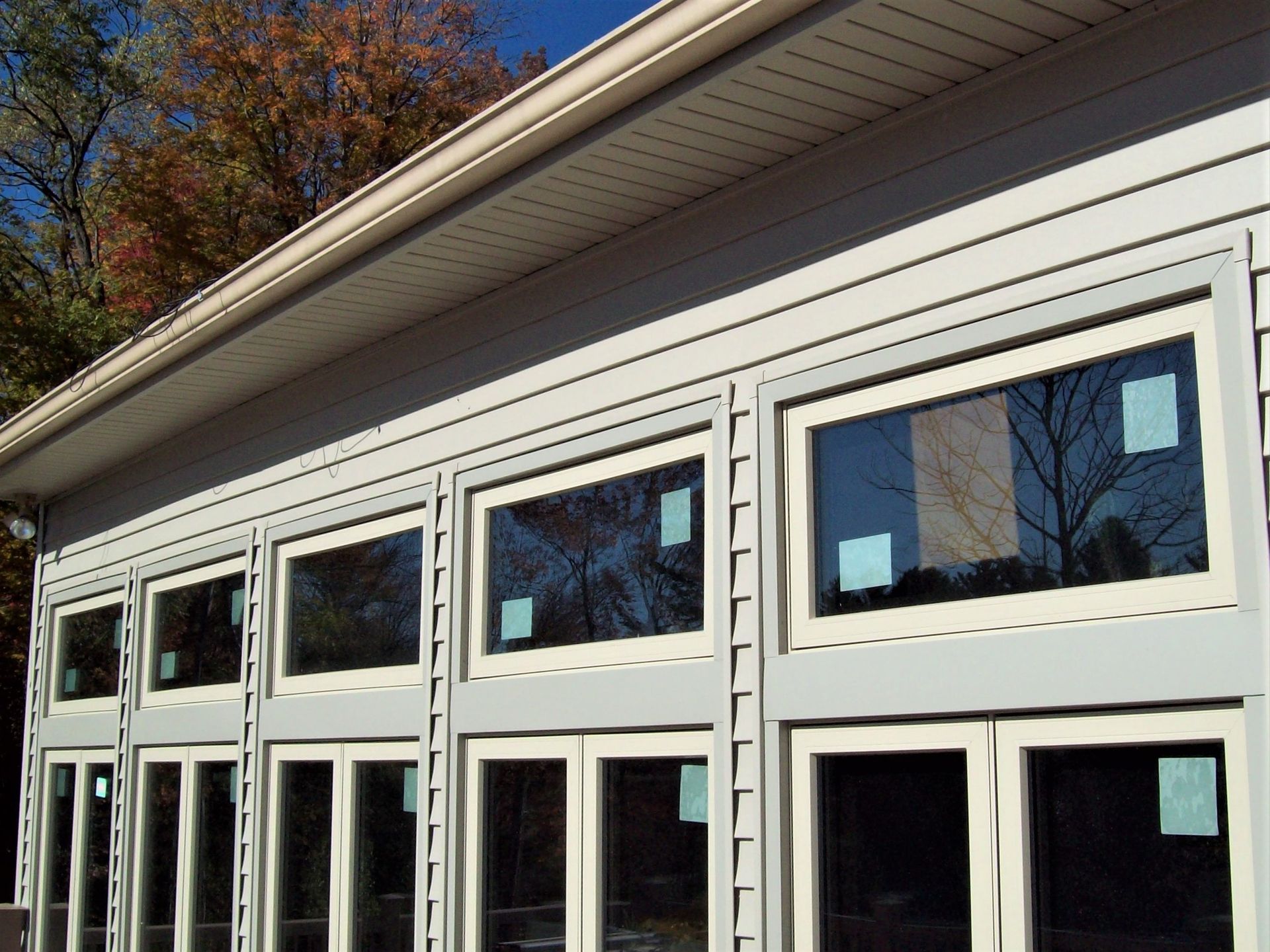 White building facade with large glass windows and doors under a sloped roofline