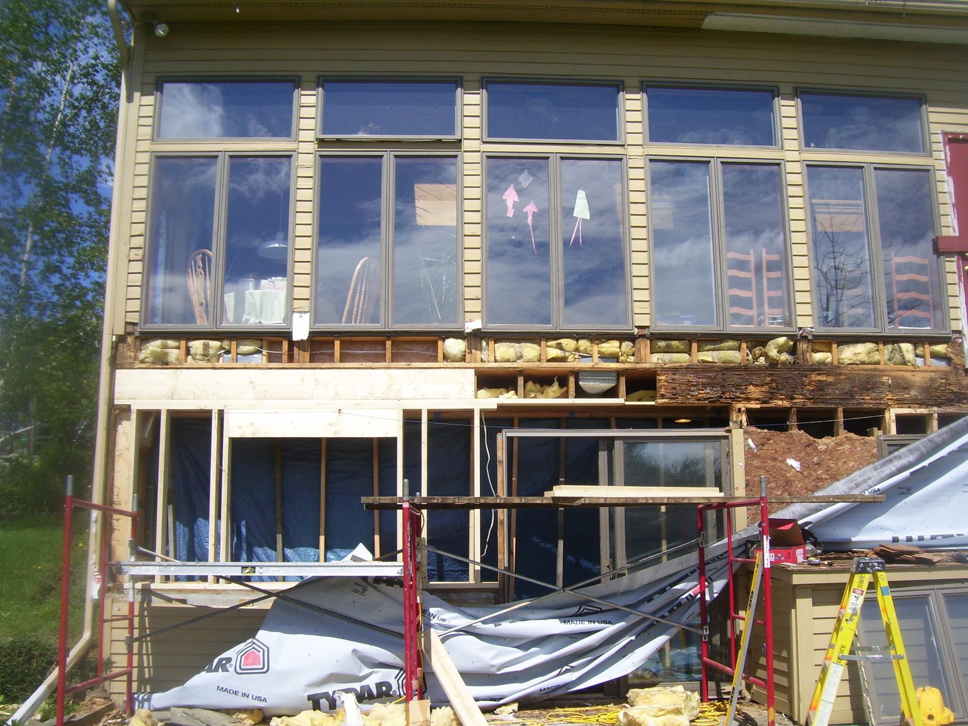Partially built house with large windows, exposed framing, and scaffolding in front