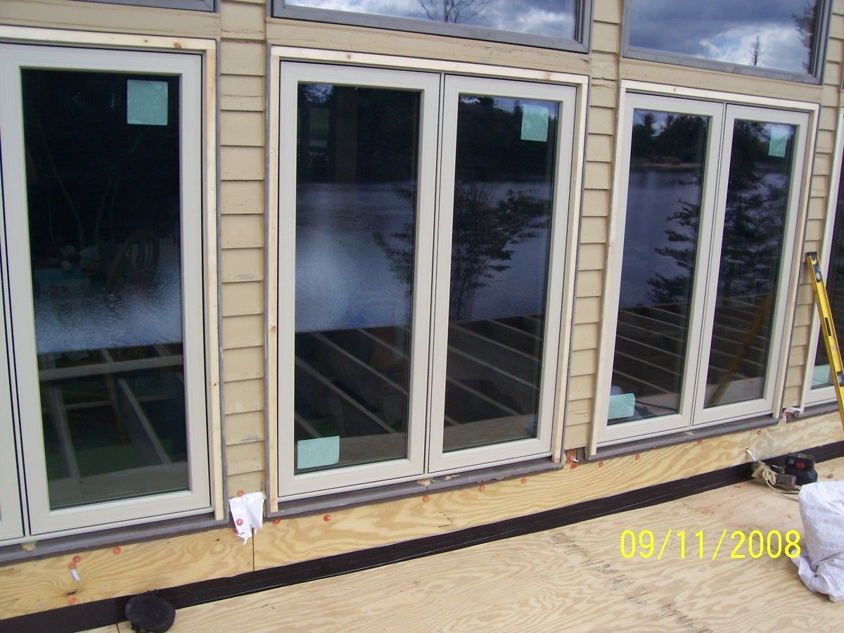 Sliding glass doors of a house with a deck and black snow barrier along the base