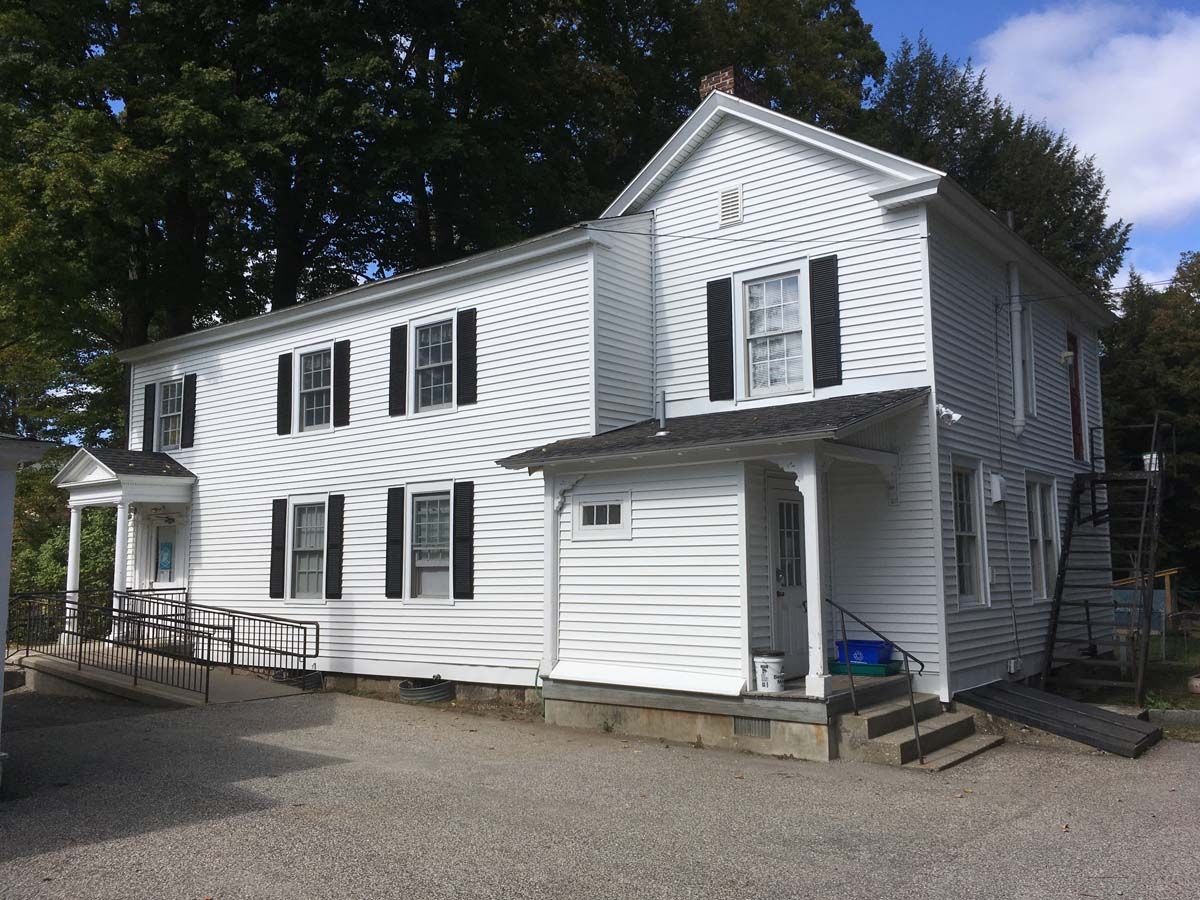 White two-story house with black shutters and a small garage, viewed from the driveway