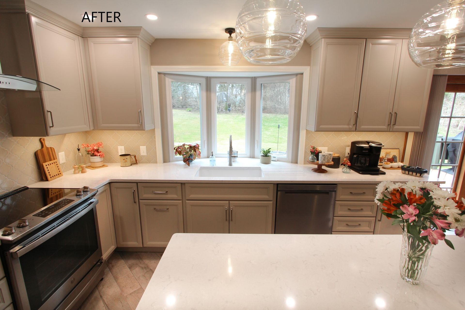 Bright modern kitchen with white countertops, gray cabinets, and a window over the sink