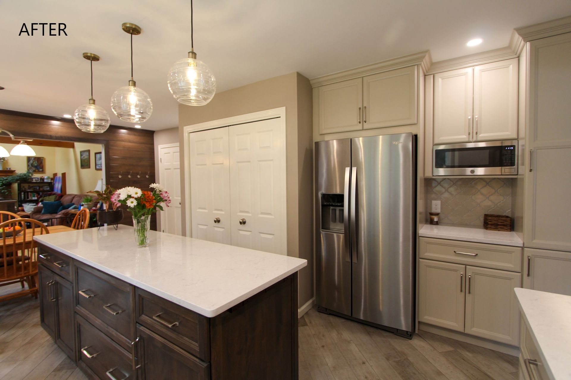 Modern kitchen with stainless steel appliances, white cabinets, island, and pendant lights