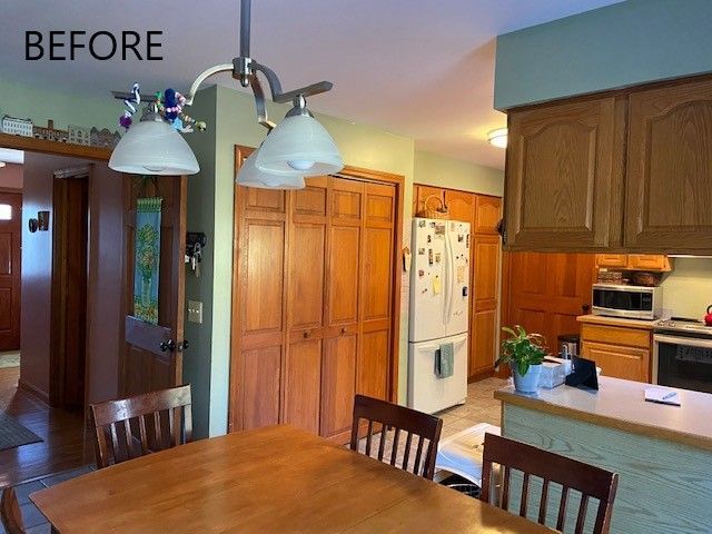 Before view of a kitchen and dining area with wood cabinets, white appliances, and a hanging light fixture