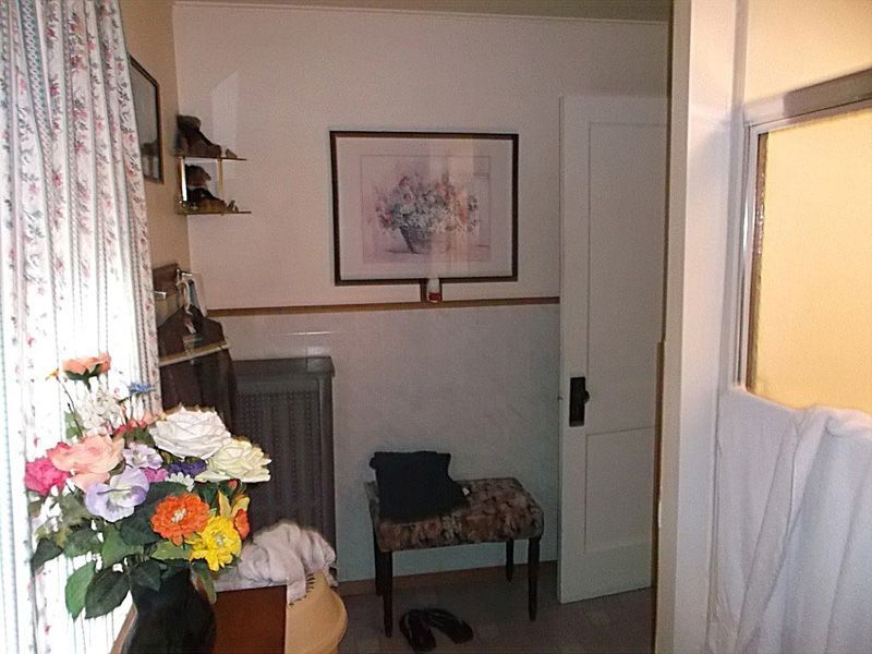 Cozy room with floral curtains, a vase of flowers, chair, and framed wall art near a doorway