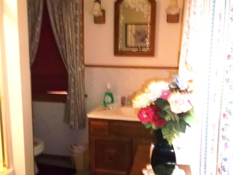 Cozy room corner with wooden cabinet, flowers in vase, framed art, and window with curtains