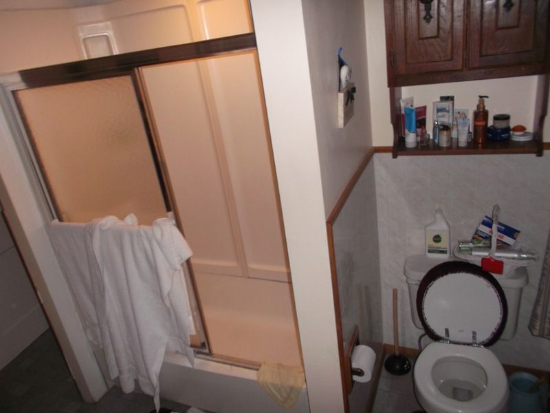 Small bathroom with a toilet, shower, and towels hanging on the shower door.