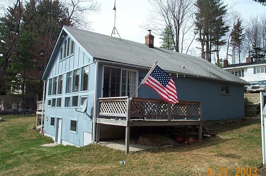 Blue house with screened porch and American flag in a grassy yard