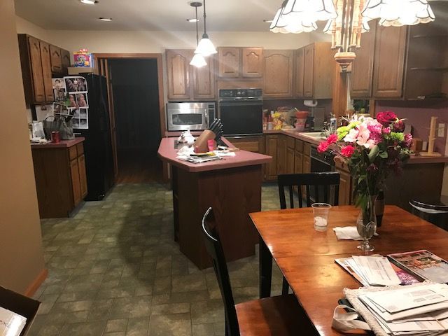 Kitchen and dining area with wooden cabinets, island, table, flowers, and hanging lights