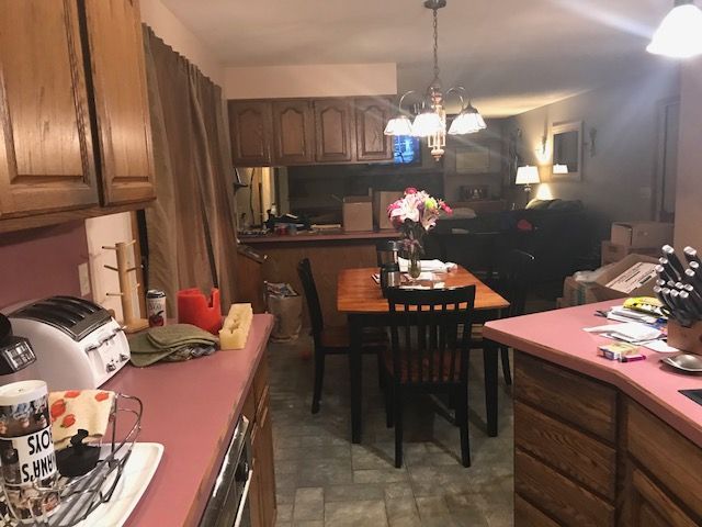 Kitchen with wooden cabinets, pink countertops, and a dining table with flowers in the center.