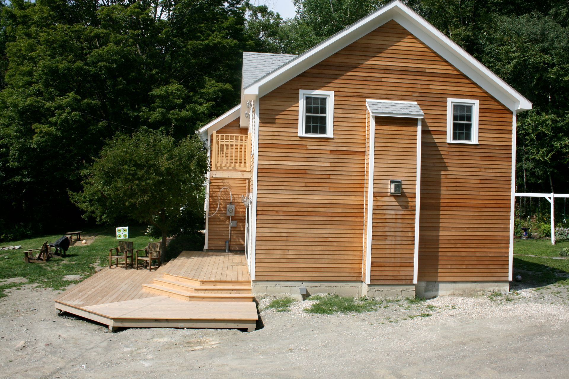 Small wooden cabin with a ramp and deck in a wooded yard