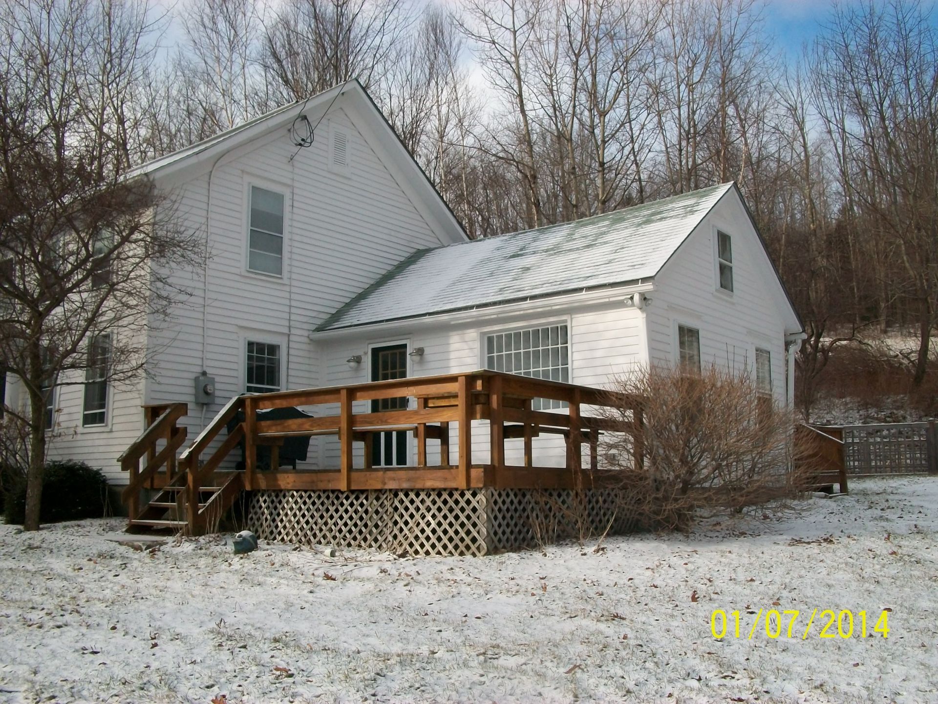 White house with wooden deck in a snowy wooded yard