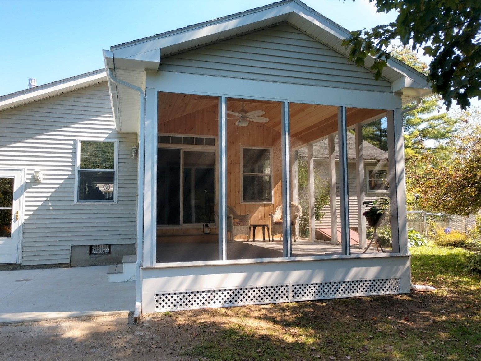 Screened porch with white siding attached to a house, viewed from the yard.