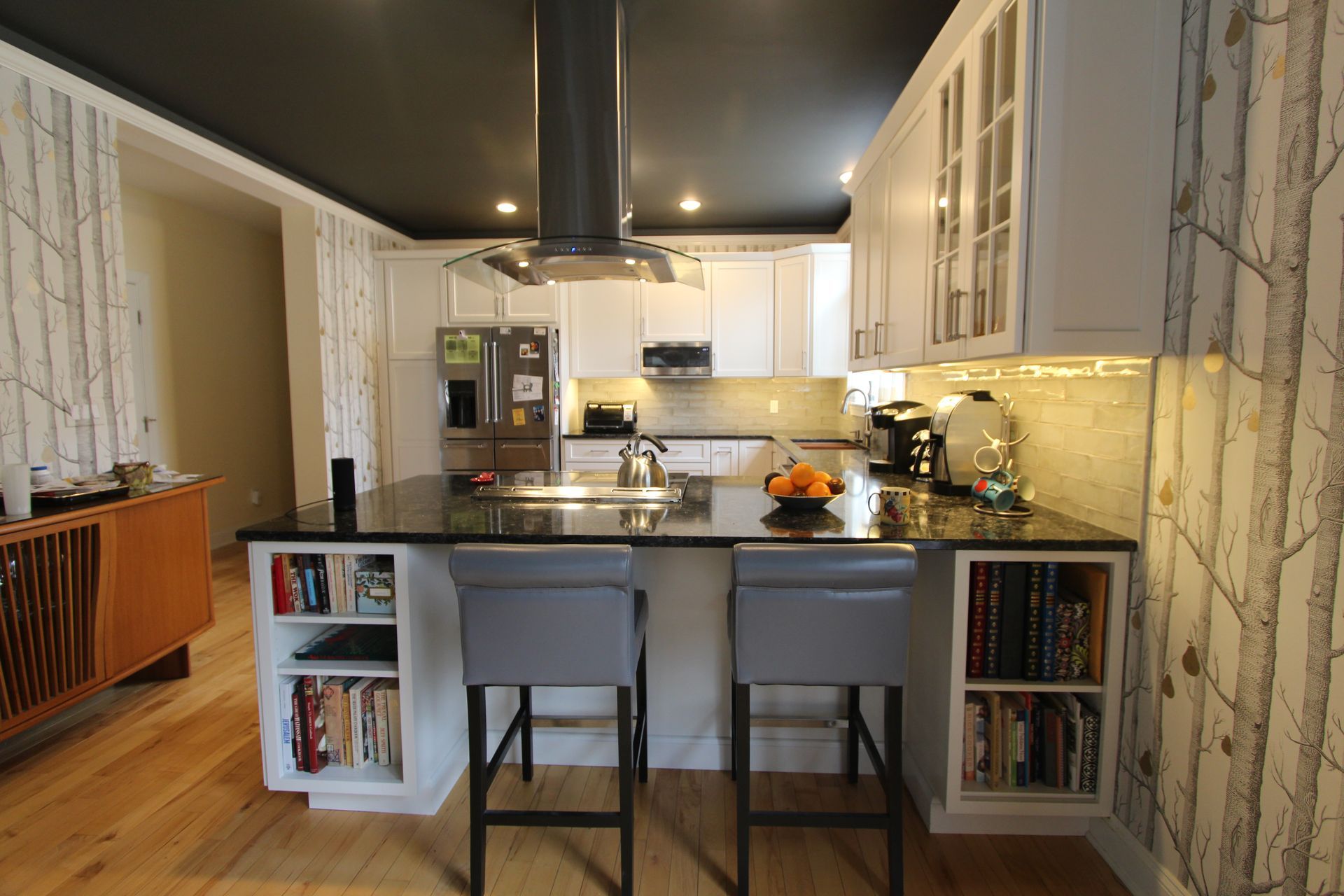 Modern kitchen with white cabinets, central island, two stools, and stainless-steel appliances