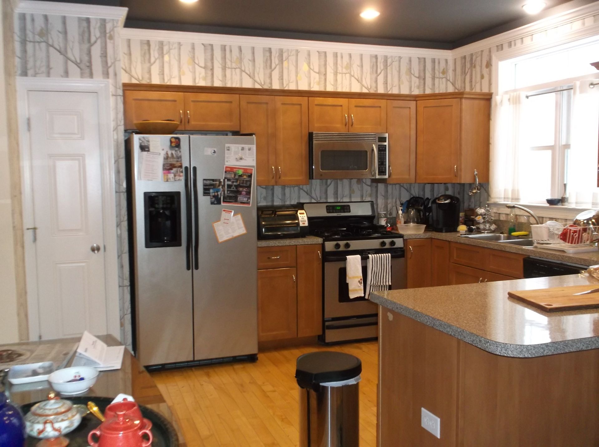 Bright kitchen with stainless steel appliances, wooden cabinets, and a granite island countertop.