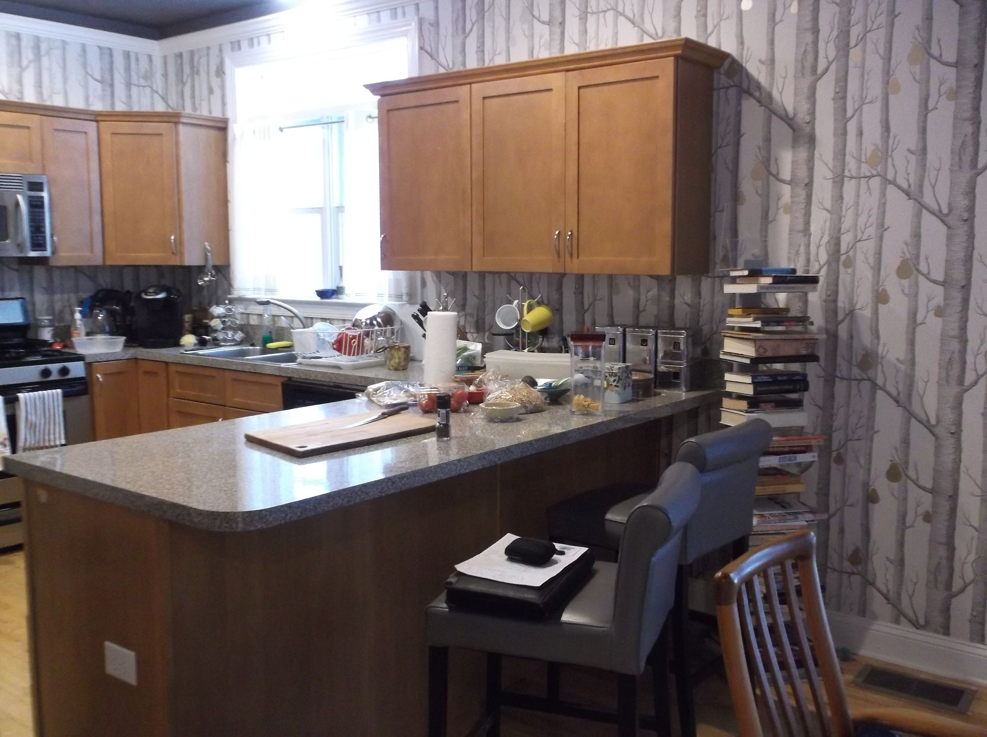 Modern kitchen with wood cabinets, granite island, bar stools, and a window over the sink.